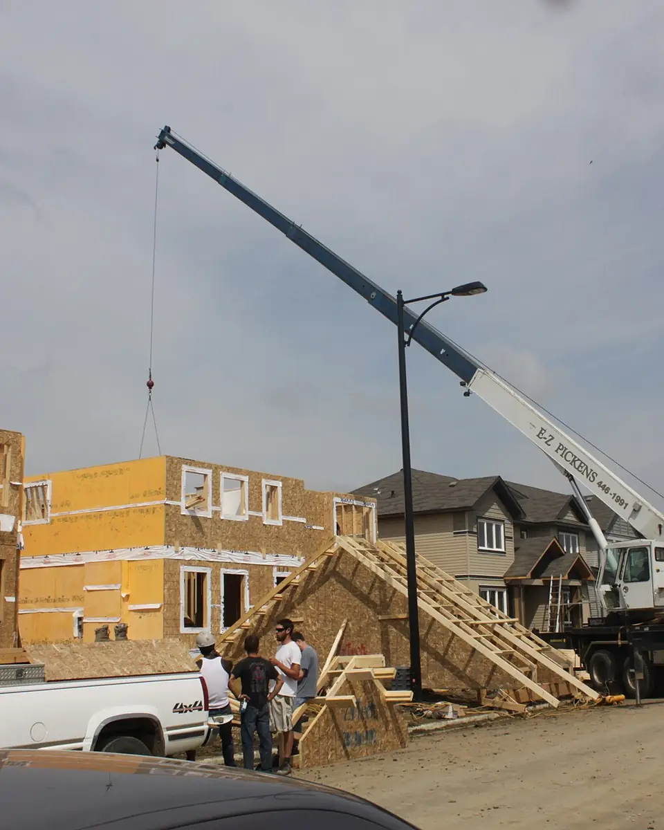 Boom truck setting roof trusses on a house under construction