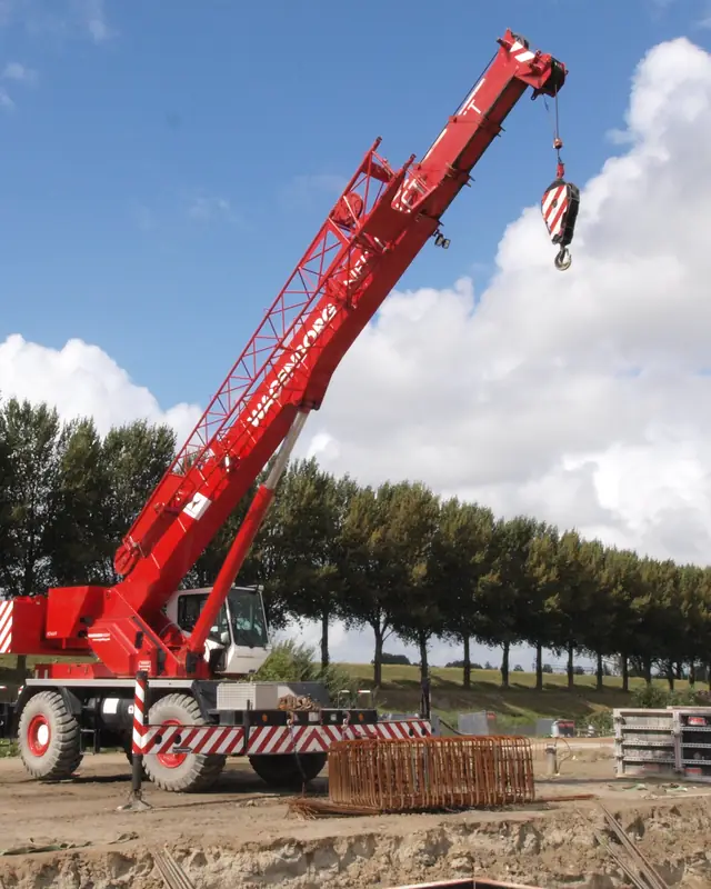 Rough terrain crane on a gravel work site with its outriggers set